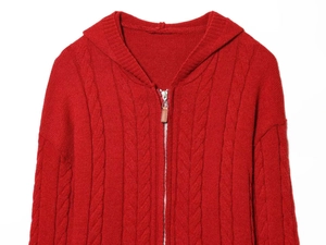 Detail of red cable-knit hooded cardigan featuring a silver zipper and brown leather puller