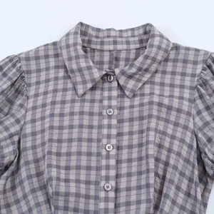 Detail view of plaid shirt with puff sleeves, lapel collar and transparent buttons