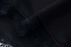 Close-up of elegant black floral eyelash lace and fabric detail on the dress