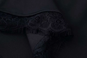 Detail of elegant black lace dress featuring delicate floral embroidery and eyelash trim