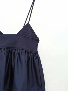 Detail of navy knit bodice with spaghetti straps and pleated satin patchwork hem