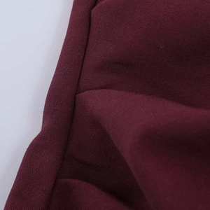 Détail macro du tissu bordeaux montrant la texture fine et la couture à double aiguille