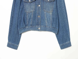 Detail of blue wash denim jacket with button flap pockets and contrast stitching