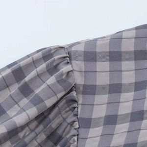 Detailed macro view of gray plaid dress fabric with elegant gathering at the shoulder seam