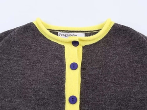 Dettaglio del cardigan grigio in maglia con colletto a coste giallo e tre bottoni viola