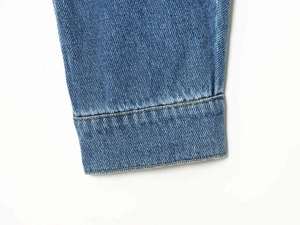 Detailed macro view of vintage washed blue denim fabric with yellow double stitching accents