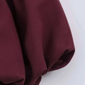 Gros plan détaillé montrant la texture plissée de la robe ballon bordeaux ajustée
