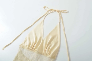Detail of backless beige halter top featuring satin fabric and intricate lace patchwork