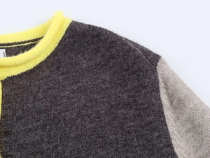 Dettaglio del cardigan in maglia grigia con colletto a coste giallo neon vivace