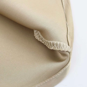 Primer plano detallado de la costura overlock y el dobladillo de un vestido midi beige