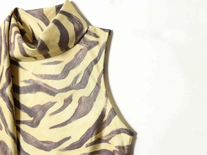 Detail of zebra print sleeveless top featuring elegant neck scarf and high collar design