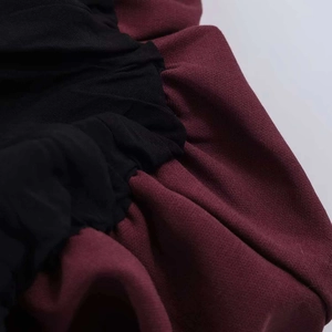 Gros plan détaillé du mousseline noire plissée et du tissu en maille bordeaux sur la robe