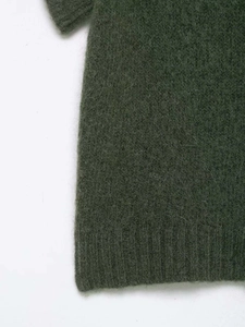 Detail of dark green knit vest showing soft mohair texture and ribbed hem craftsmanship