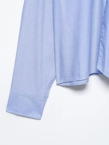 Close-up detail of light blue woven shirt fabric texture and high-quality stitching seams
