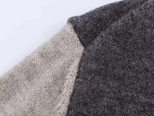Dettaglio della trama in maglia bicolore gialla e grigia su un cardigan morbido