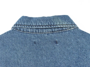 Detail of classic collar and golden stitching on washed blue denim jacket for women