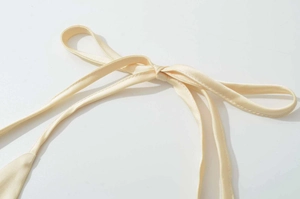 Detailed close-up of cream satin ribbon tie on backless dress with smooth silk texture