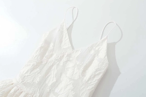Detail of white V-neck strap dress featuring textured floral jacquard fabric