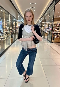 Chic layering detail of a V-neck lace camisole over a long sleeve top with slim jeans