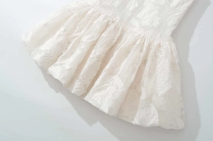 Detail of white dress featuring intricate floral embroidery and textured jacquard fabric