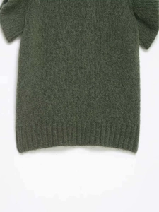 Detail of dark green mohair knit top showing soft textured fabric and ribbed hem finish
