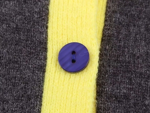 Dettaglio macro di un cardigan in maglia a righe gialle e grigie con bottone viola