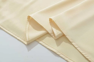 Close-up of light yellow chiffon dress hemline with professional flat-seam stitching
