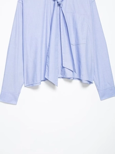 Close-up of light blue shirt with a bow-knot collar and fine twill fabric texture