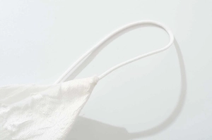 Detail of white textured lace fabric with thin elastic strap on V-neck dress