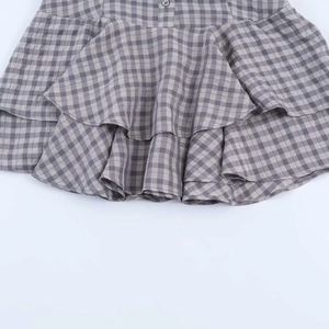 Detail of layered ruffle hem and gray plaid pattern on a summer mini dress