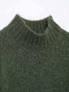 Detailed macro view of dark green mohair knit sweater with ribbed mock neck collar texture