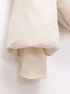 Detail of windproof beige puffer jacket showing inner ribbed knit cuffs for warmth