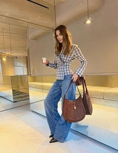 Brown suede hobo shoulder bag with gold metal clasp shown in a minimalist interior setting
