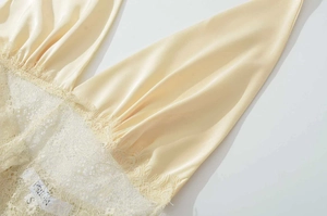 Macro detail of champagne satin dress with delicate eyelash lace trim and size S label