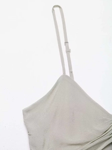 Detail of adjustable thin shoulder strap with silver buckle on V-neck camisole