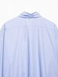 Close-up of light blue shirt collar back with button loop detail and fine stitching