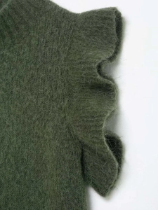 Close-up of dark green wool knit top featuring elegant layered ruffle details on shoulder