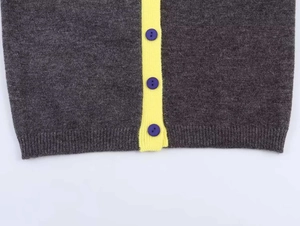 Dettaglio cardigan in maglia grigia con abbottonatura gialla e bottoni viola