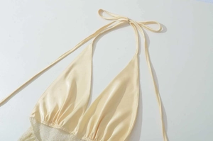 Detailed view of champagne satin halter top with delicate lace trim and silk texture