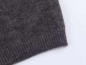 Dettaglio del cardigan in maglia grigio scuro con polsini a costine e trama di lana