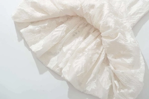 Detailed macro view of white dress hem with 3D floral jacquard embossed texture