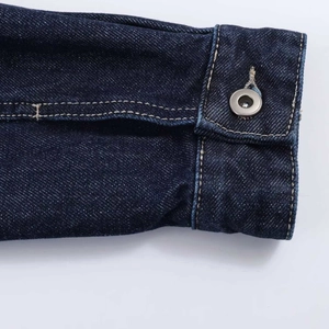 Détail du tissu denim sergé bleu foncé avec boutons métalliques et surpiqûres