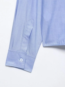 Detailed close-up of light blue shirt sleeve with button and high-quality fabric texture