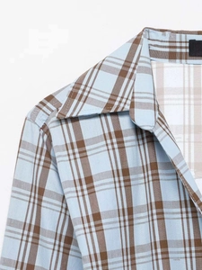 Detail of the plaid shirt collar featuring light blue and brown woven fabric texture