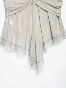 Close-up of sage green camisole featuring delicate pleated design and eyelash lace trim