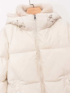 Detail of hooded winter jacket showing beige quilted fabric and fluffy faux fur trim
