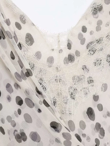Détail de bordure en dentelle élégante et pois gris sur un caraco blanc d'été
