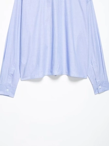 Detail of light blue shirt cuff with white button and high-quality fabric texture