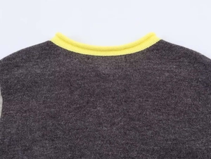 Dettaglio del cardigan in maglia grigia con colletto a coste gialle e trama fine