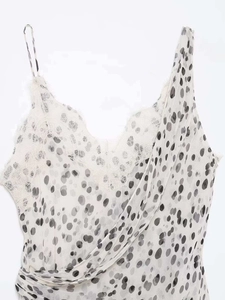 Détail rapproché du haut blanc à pois avec bordure en dentelle de cils au décolleté en V